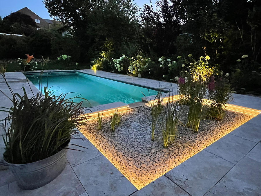 Schwimmbadbeleuchtung: Pool mit beleuchtetem Kiesbeet und angestrahlten Hortensien in der Dämmerung