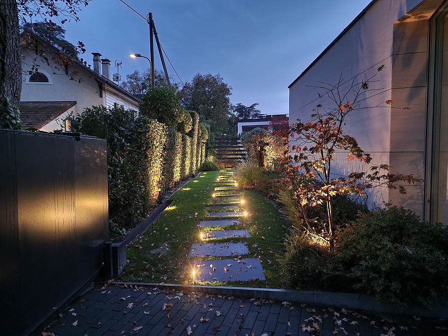 Wegbeleuchtung: Trittplatten mit Bodenleuchten entlang einer angestrahlten Hecke