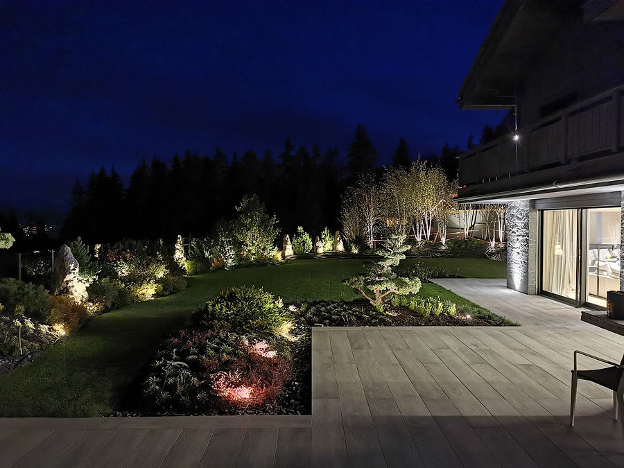 Chalet-Terrasse mit beleuchtetem Garten, Formgehölz und Birken zur blauen Stunde