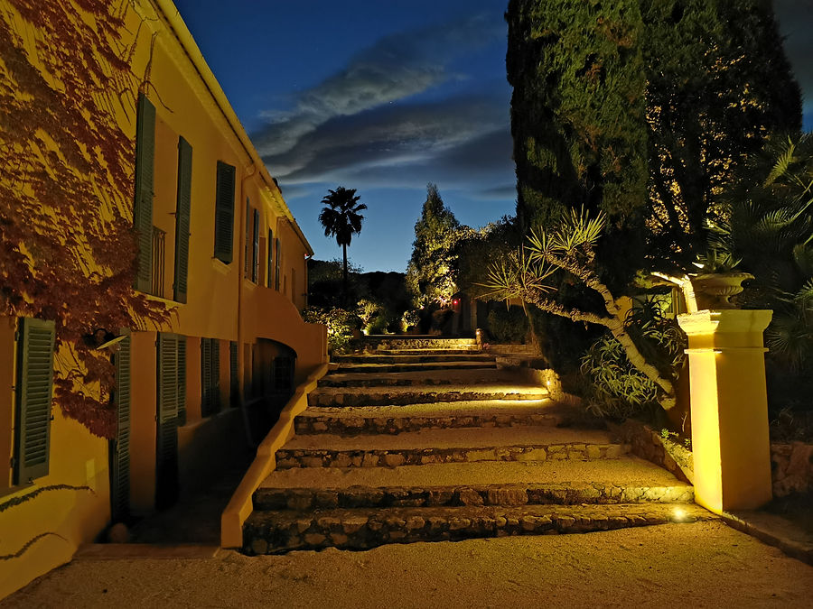 Beleuchtete Natursteintreppe entlang einer mediterranen Villa zur blauen Stunde